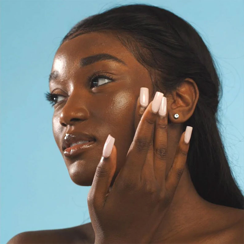 ABSOLUTE NEW YORK model applying hydrating primer drops to cheek for dewy hydrated makeup base