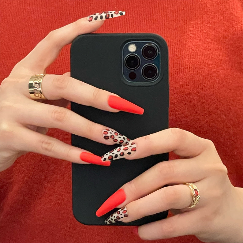 Hands holding phone showing IVY BEAUTY by KISS leopard print press on nails and coral matte tips