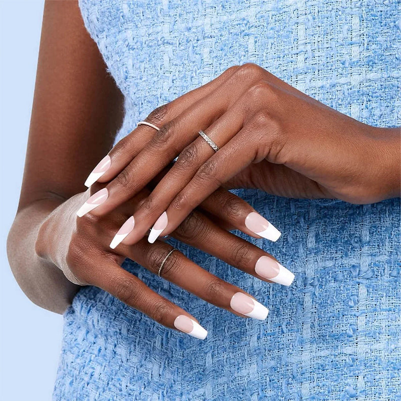 Kiss Salon Acrylic French nails on model hands with white tips and natural pink base wearing delicate silver rings and blue dress