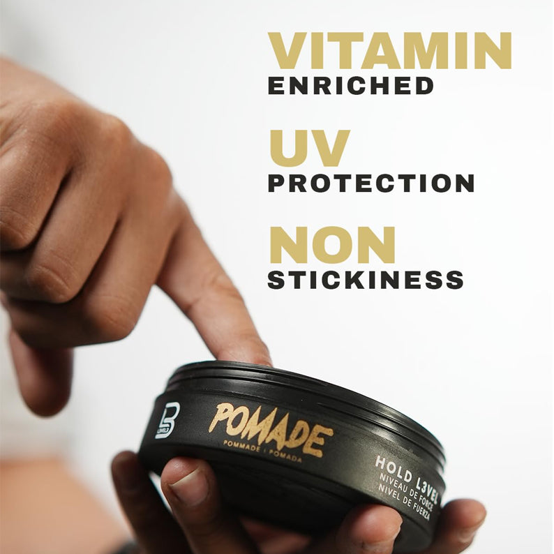 L3VEL3 keratin infused hair pomade in black tin held by hand with finger dipping into product