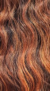 Close up of wavy auburn and caramel hair texture on NUTIQUE Illuze Livia HD lace wig.