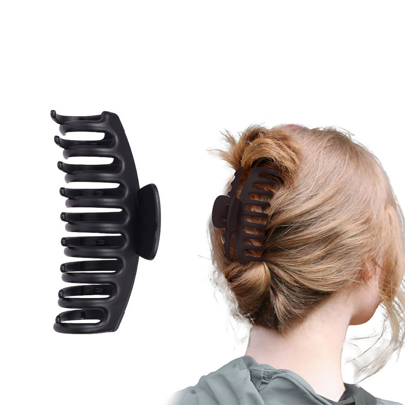large matte black butterfly hair clip shown in product shot and securing a twisted low bun on blonde hair