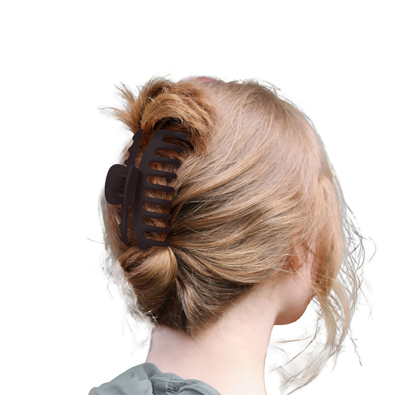 Large matte black butterfly hair clip securing a messy blonde bun on a woman for casual everyday styling