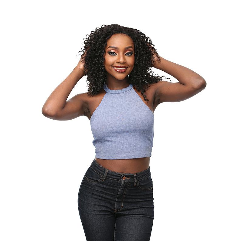 Smiling woman with curly unprocessed Brazilian virgin hair wearing a blue crop top and dark jeans